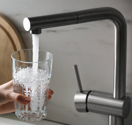 Glass being filled with water from a modern kitchen faucet.